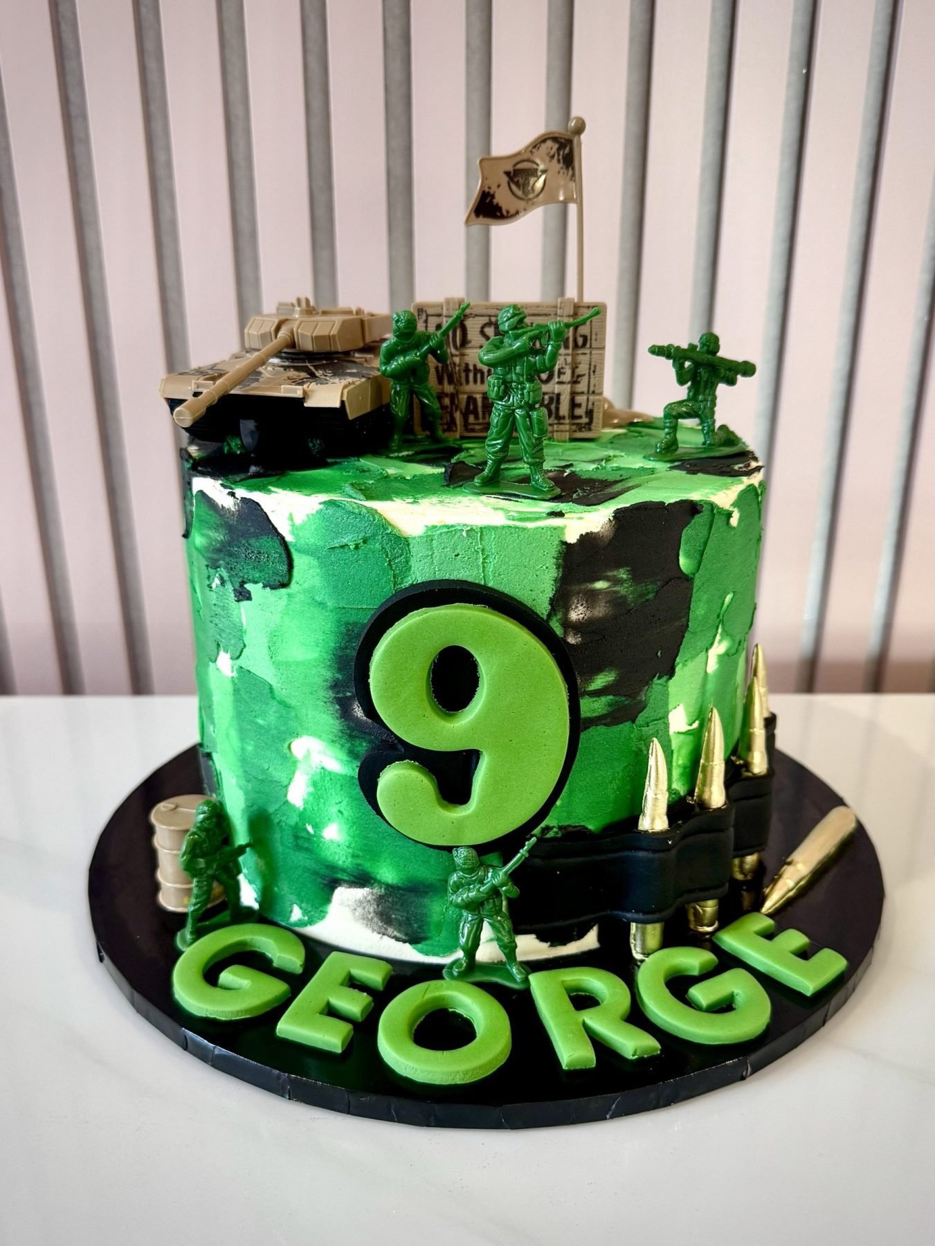 Army themed birthday cake with green camouflage buttercream, toy soldiers, tank and bullet decorations