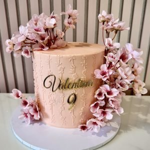 Pink cherry blossom birthday cake with buttercream finish, floral embossing and cascading blossom decorations