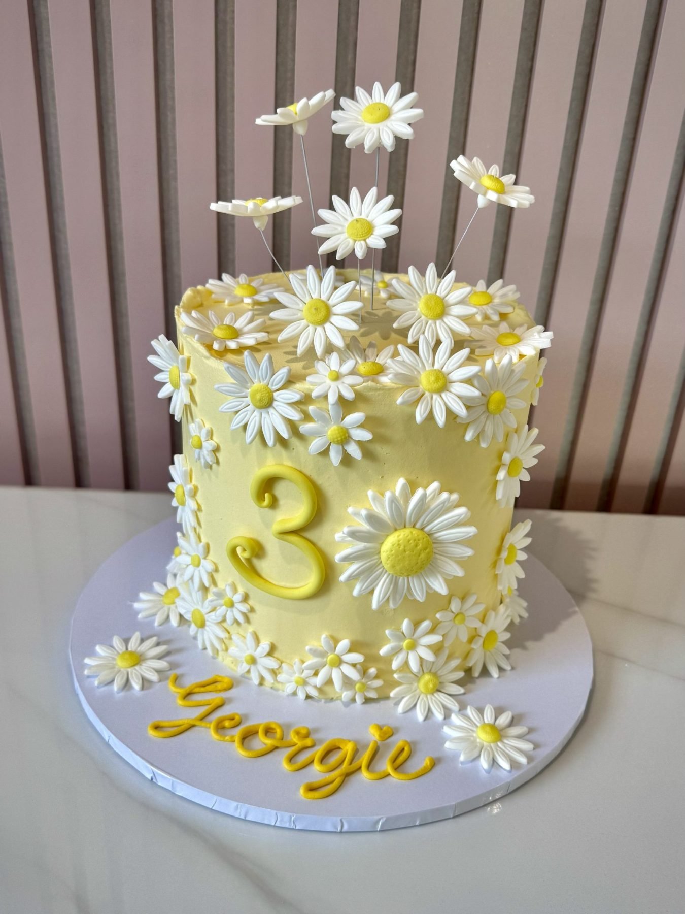 Yellow buttercream daisy birthday cake with white fondant flowers and elevated floral decoration