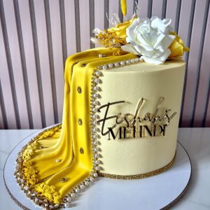 Yellow mehndi cake with draped design, pearl detailing, gold accents and floral decoration