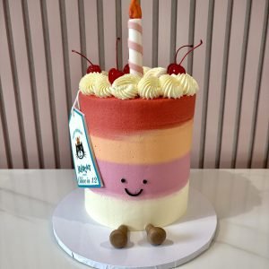 jellycat style birthday cake with pastel stripes, smiley face and candle topper