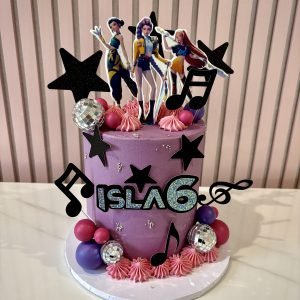 K-pop themed birthday cake with character toppers, music notes, stars and pink and purple design