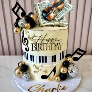 Music themed birthday cake with piano keys, edible violin on sheet music, gold accents and musical notes decorations