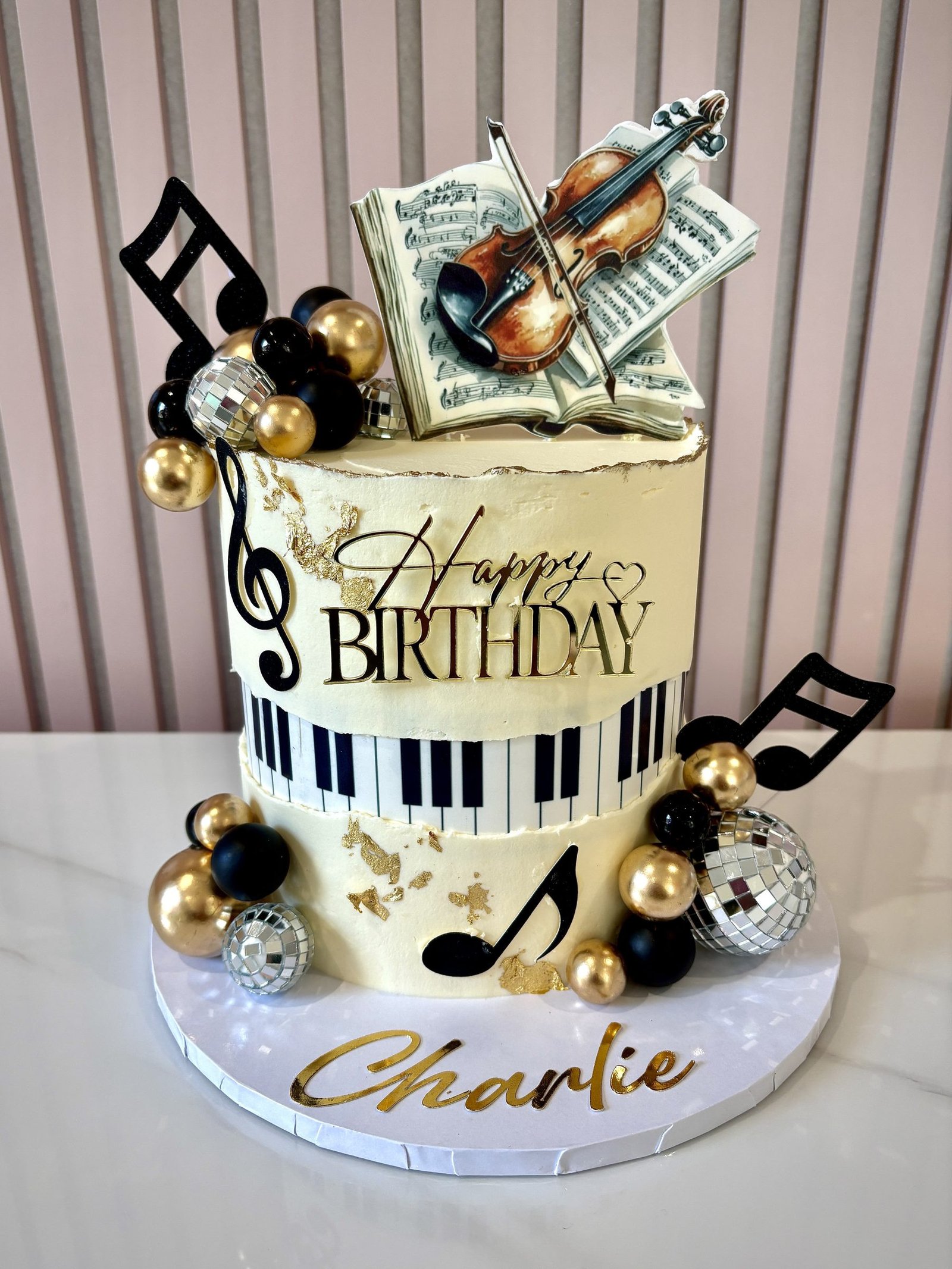 Music themed birthday cake with piano keys, edible violin on sheet music, gold accents and musical notes decorations