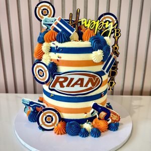 Nerf themed birthday cake with blue and orange buttercream stripes, target decorations and blaster details