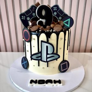 PlayStation themed birthday cake with black drip icing, gaming controller symbols, chocolate toppings and PlayStation logo