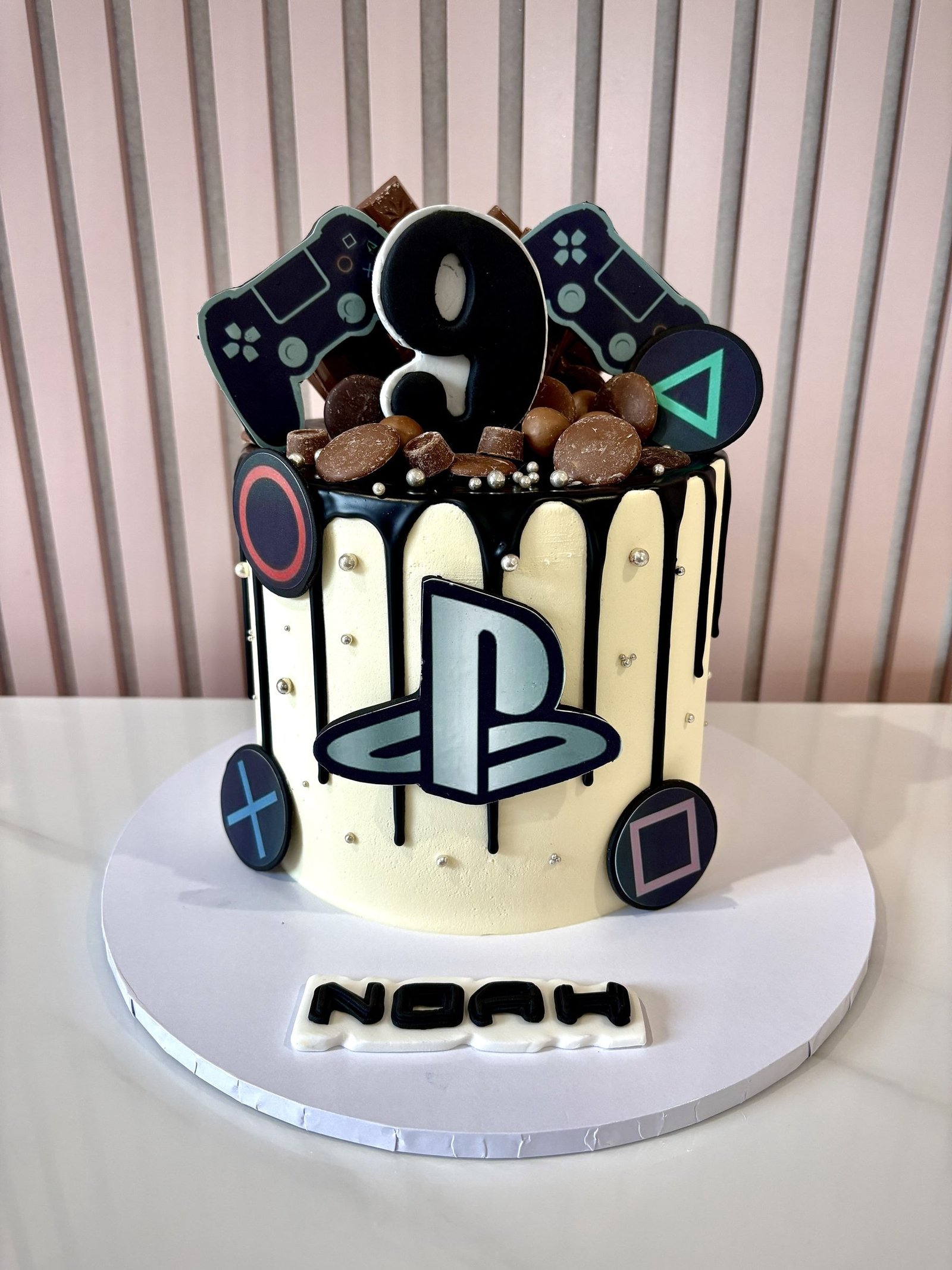 PlayStation themed birthday cake with black drip icing, gaming controller symbols, chocolate toppings and PlayStation logo