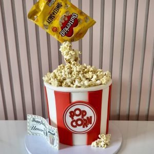 Popcorn gravity birthday cake with red and white bucket design and floating popcorn effect from bag
