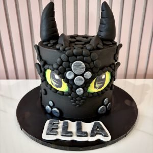 Toothless inspired black buttercream cake with dragon eyes and textured details for a themed birthday