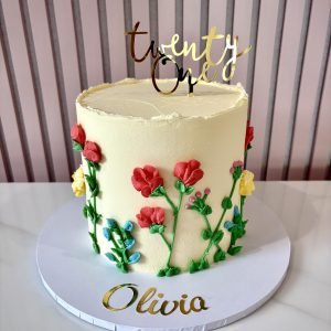 Buttercream birthday cake with hand piped wildflowers in bright colours on a smooth ivory finish with elegant styling