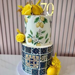 Amalfi Coast themed two tier cake with blue tile pattern, lemon design and yellow floral accents