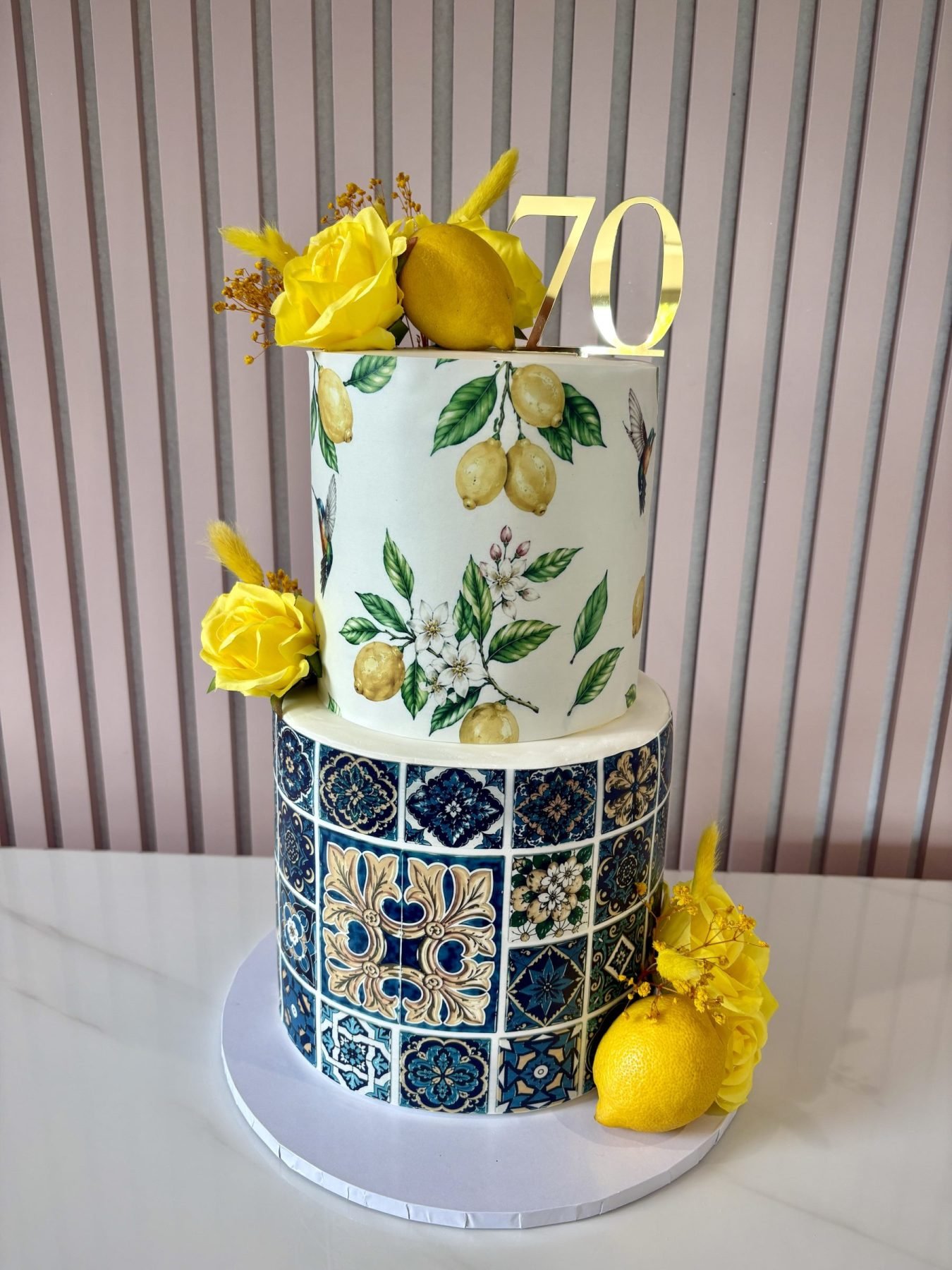 Amalfi Coast themed two tier cake with blue tile pattern, lemon design and yellow floral accents