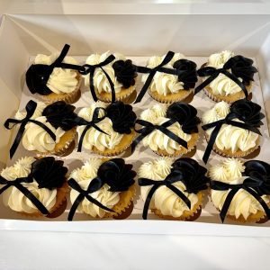 Elegant cupcakes with vanilla buttercream swirls, black fondant ruffles and satin ribbon bows in a monochrome design