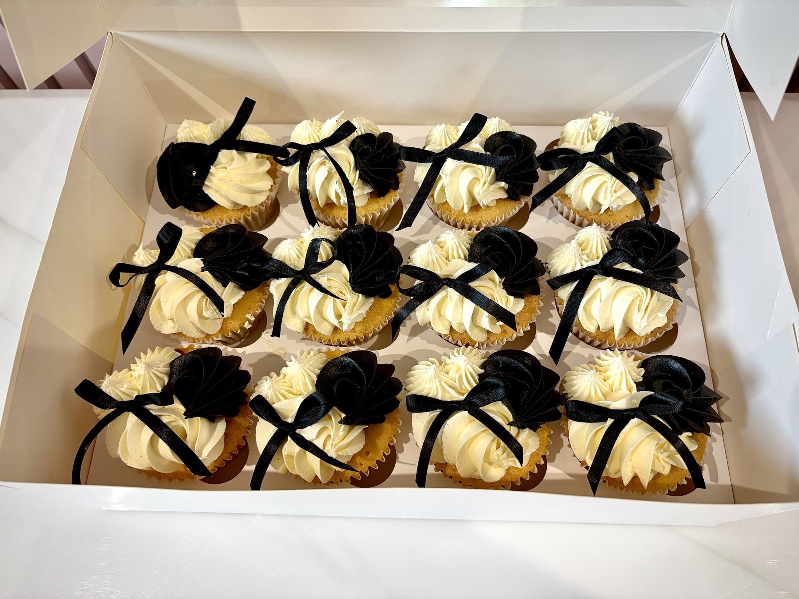 Elegant cupcakes with vanilla buttercream swirls, black fondant ruffles and satin ribbon bows in a monochrome design