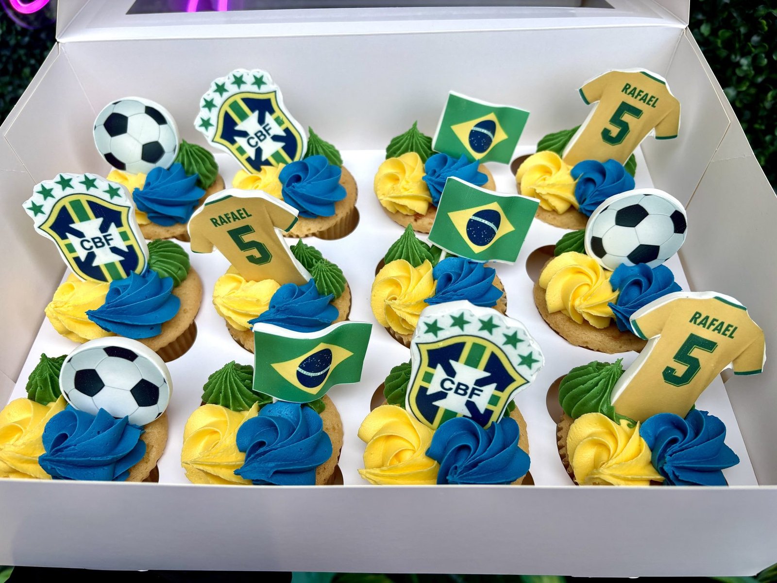 Brazil football themed cupcakes with personalised shirt toppers, football decorations and yellow green and blue buttercream swirls