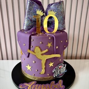 Purple cheerleader birthday cake with glitter bow topper, gold stars and cheerleader silhouette decoration.