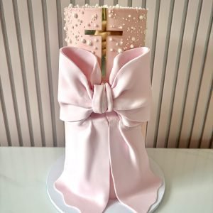 Elegant christening cake with fondant bow drape and gold cross detail