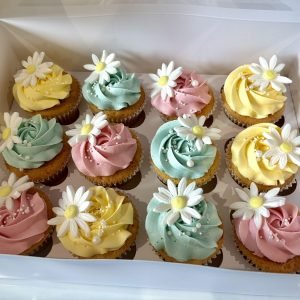 Pastel daisy cupcakes with pink yellow and mint buttercream swirls, floral toppers and pearl sprinkles