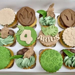 Dinosaur themed cupcakes with green buttercream, fossil toppers, jungle leaves and personalised name and age design