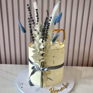 Elegant ivory buttercream cake decorated with dried flowers, lavender, gold leaf accents and a customisable number topper.