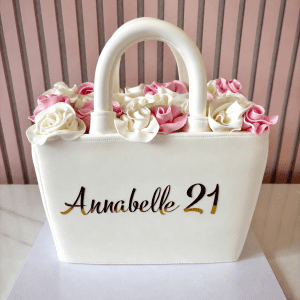 Elegant handbag shaped birthday cake with fondant finish and pink and ivory roses on top