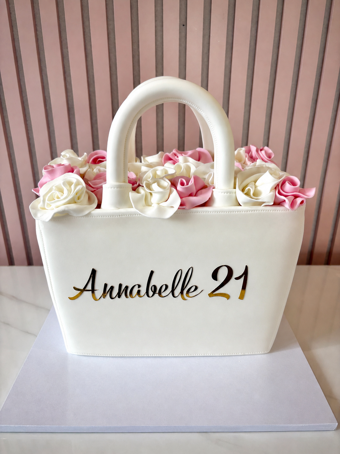 Elegant handbag shaped birthday cake with fondant finish and pink and ivory roses on top
