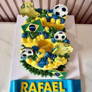 Football themed number cake with Brazil inspired colours, football toppers and colourful buttercream piping