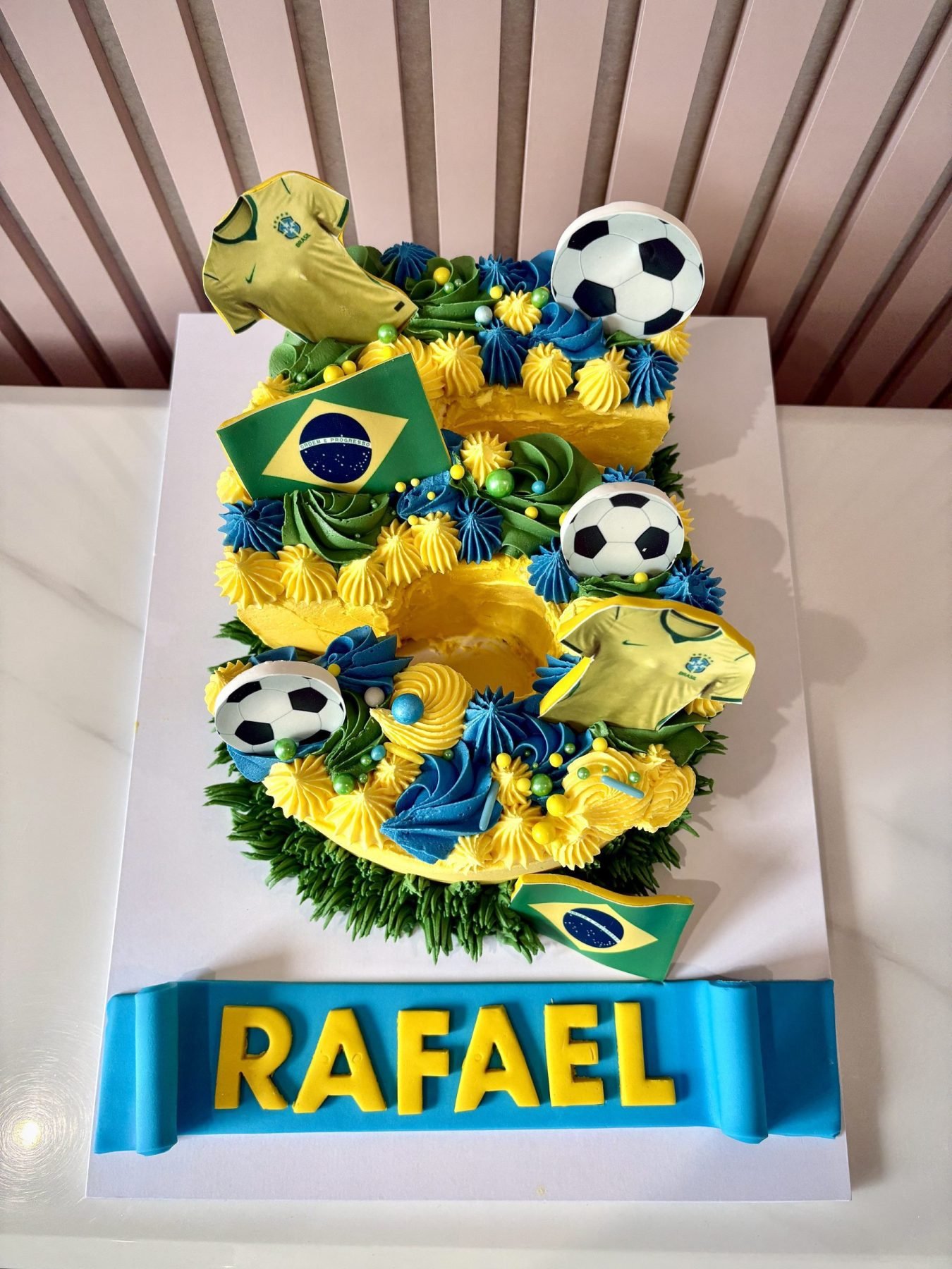 Football themed number cake with Brazil inspired colours, football toppers and colourful buttercream piping