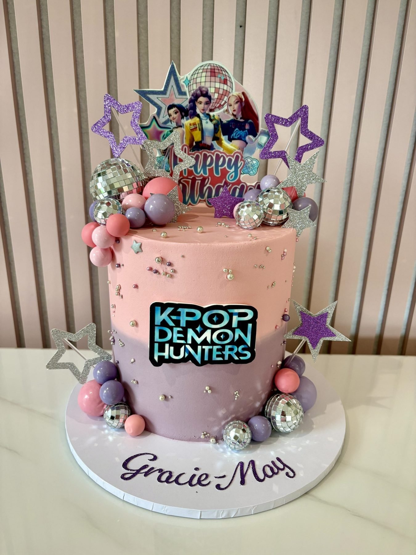 KPop Demon Hunters birthday cake with pastel colours, glitter stars, disco balls and themed toppers