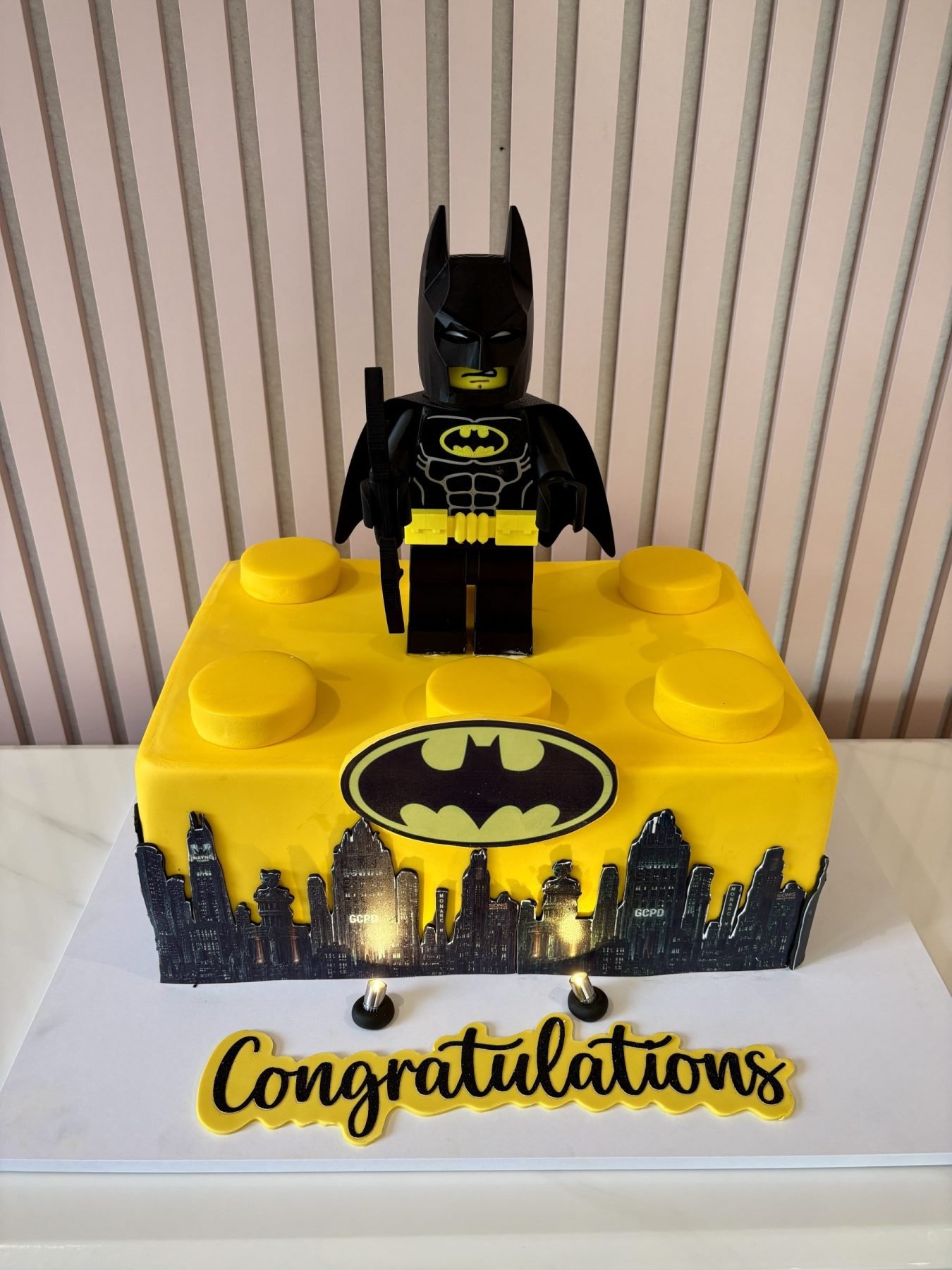 Lego Batman birthday cake for boys with giant Lego brick design, Gotham City skyline and Lego Batman figure topper.