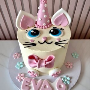 Pastel kitty birthday cake with fondant cat face, pink bow, pastel flowers and unicorn style horn