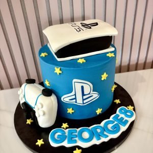 PlayStation themed birthday cake with PS5 console topper, controller and blue gaming design