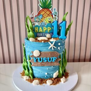 SpongeBob themed birthday cake with underwater decorations, seashells, seaweed accents and character toppers