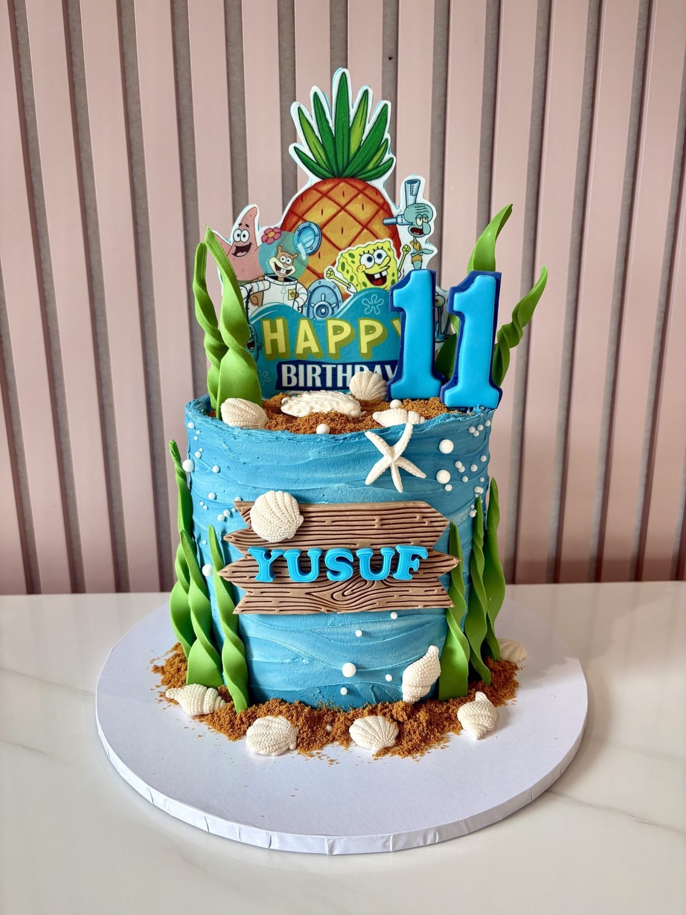 SpongeBob themed birthday cake with underwater decorations, seashells, seaweed accents and character toppers