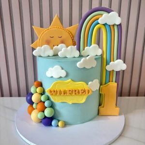 Pastel rainbow and sunshine cake with clouds, colourful balloon decorations and a customisable number topper.
