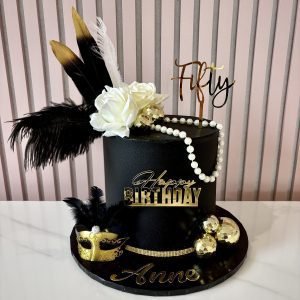 Black and gold Great Gatsby birthday cake with decorative feathers, pearls, roses and Art Deco-inspired styling.