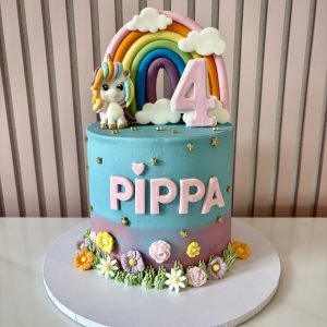 Unicorn birthday cake with rainbow topper, pastel colours, sugar flowers and gold star decorations.